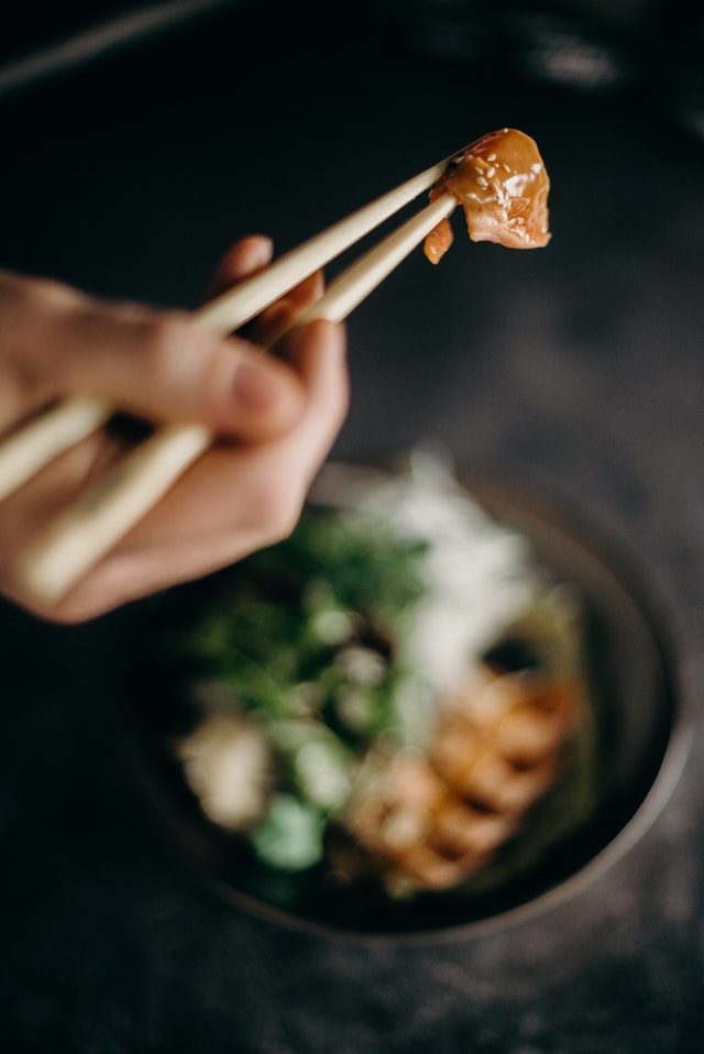 hand holding food with chopsticks