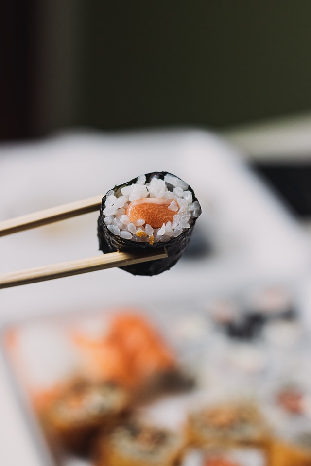 sushi being held with chopsticks